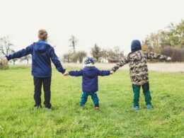 three children holding hands standing on grasses